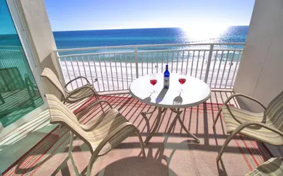 a table and chairs on a balcony with the ocean at Aqua 0506 in Panama City Beach