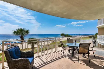 a patio with a table and chairs and the beach at Aqua 0208 in Panama City Beach
