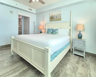 a bedroom with a large white bed and a nightstand at Aqua 0502 in Panama City Beach
