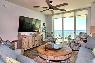 a living room with a tv and a table and chairs at Aqua 0502 in Panama City Beach