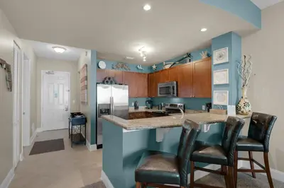 a kitchen with blue walls and a island with bar stools at Aqua 2207 in Panama City Beach