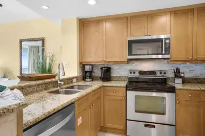 a kitchen with wooden cabinets and stainless steel appliances at Aqua 0610 in Panama City Beach