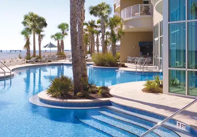 a large swimming pool with palm trees and a building at Aqua 0610 in Panama City Beach