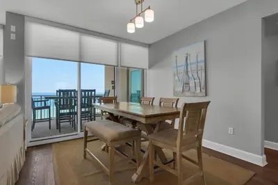 a dining room with a table and chairs and a balcony at Aqua 0302 in Panama City Beach