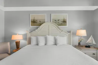 a bedroom with a large white bed with two lamps at Aqua 0302 in Panama City Beach