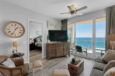a living room with a clock on the wall and a television at Aqua 2306 in Panama City Beach