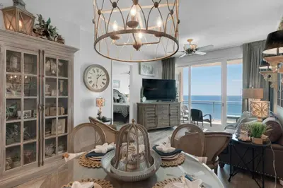a living room with a table and chairs and a clock at Aqua 2306 in Panama City Beach