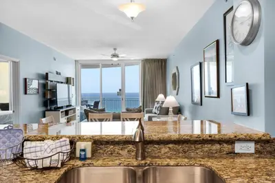 a kitchen and living room with a view of the ocean at Aqua 1008 in Panama City Beach
