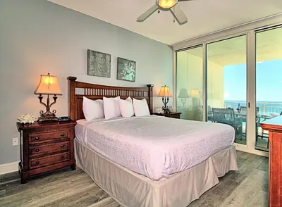 a bedroom with a large bed and a balcony at Aqua 1008 in Panama City Beach