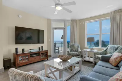 a living room with a tv and a couch and chairs at Aqua 0210 in Panama City Beach