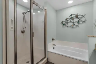 a white bathroom with a shower and a bath tub at Aqua 0210 in Panama City Beach