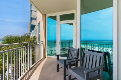 two chairs on a balcony with a view of the ocean at Aqua 0210 in Panama City Beach