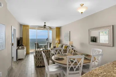a dining room and living room with a table and chairs at Aqua 1106 in Panama City Beach