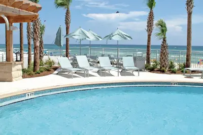 a swimming pool with chairs and umbrellas at a resort at Aqua 1106 in Panama City Beach