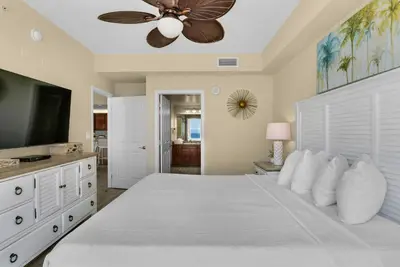 a bedroom with a large white bed with a ceiling fan at Aqua 1106 in Panama City Beach