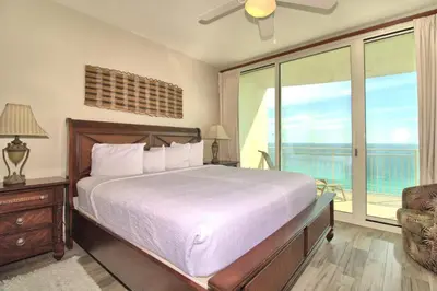a bedroom with a bed and a window with a balcony at Aqua 1703 in Panama City Beach