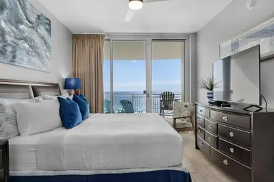 a bedroom with a bed and a television and a balcony at Aqua 0708 in Panama City Beach