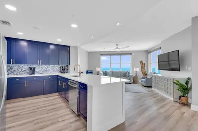 a kitchen with blue cabinets and a living room at Aqua 1501 in Panama City Beach
