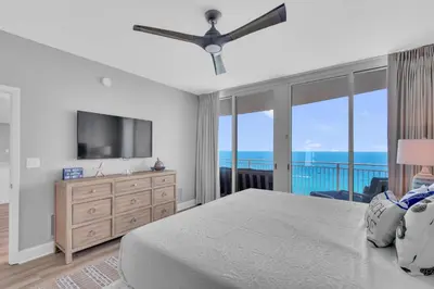 a bedroom with a bed and a television and a balcony at Aqua 1501 in Panama City Beach