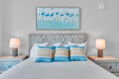 a bed with blue and white pillows and two lamps at Aqua 1501 in Panama City Beach