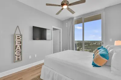 a white bedroom with a bed and a ceiling fan at Aqua 1501 in Panama City Beach
