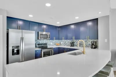 a kitchen with blue cabinets and a stainless steel refrigerator at Aqua 1501 in Panama City Beach