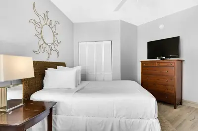 a bedroom with a bed and a dresser with a television at Aqua 1009 in Panama City Beach