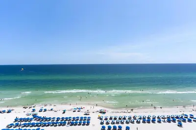 a beach with umbrellas and people in the ocean at Aqua 1009 in Panama City Beach
