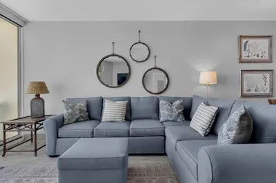 a living room with a blue couch and mirrors at Aqua 1009 in Panama City Beach