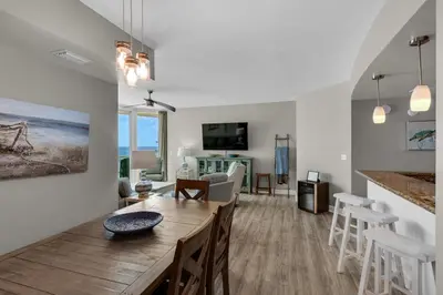a dining room and living room with a table and chairs at Aqua 0611 in Panama City Beach