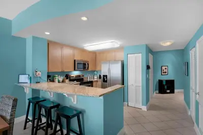 a kitchen with blue walls and bar stools at Aqua 1708 in Panama City Beach