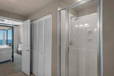 a bathroom with a shower and a glass door at Aqua 1708 in Panama City Beach