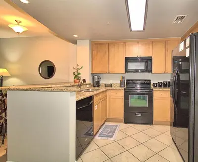 a kitchen with wooden cabinets and black appliances at Aqua 1510 in Panama City Beach