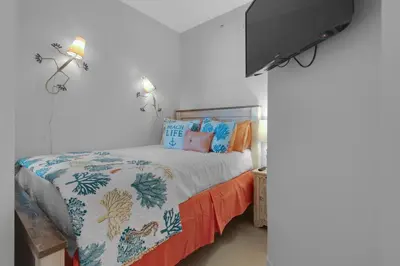 a bedroom with a bed with a comforter on it at Aqua 2110 in Panama City Beach