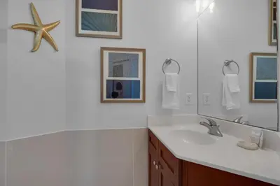 a white bathroom with a sink and a mirror at Aqua 2110 in Panama City Beach