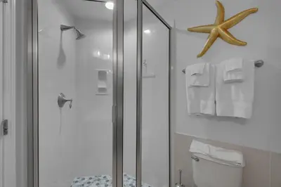 a bathroom with a shower with a toilet and a starfish at Aqua 2110 in Panama City Beach
