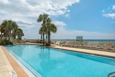 a large swimming pool with palm trees and chairs at Aqua 2110 in Panama City Beach