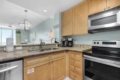 a kitchen with wooden cabinets and stainless steel appliances at Aqua 1908 in Panama City Beach