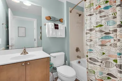a bathroom with a toilet and a shower curtain at Aqua 1908 in Panama City Beach