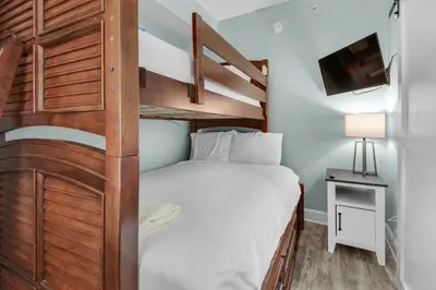 a small bedroom with a bunk bed and a tv at Aqua 1908 in Panama City Beach