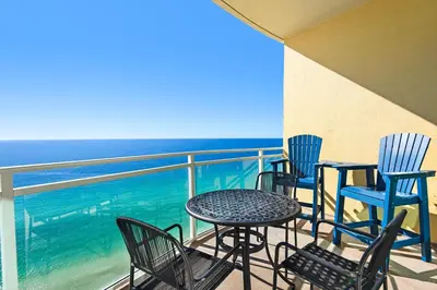 a balcony with chairs and tables and the ocean at Aqua 2304 in Panama City Beach