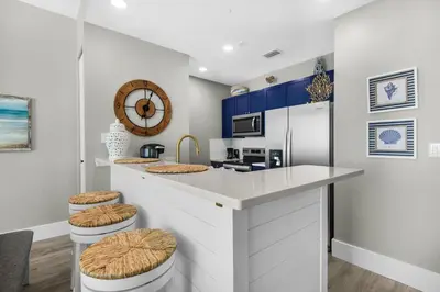 a kitchen with a counter with stools at Aqua 2304 in Panama City Beach