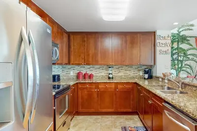 a kitchen with wooden cabinets and a stainless steel refrigerator at Aqua 1001 in Panama City Beach