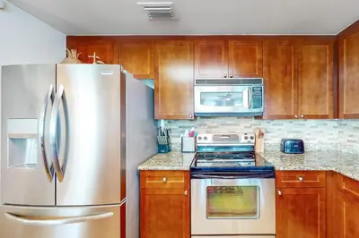 a kitchen with wooden cabinets and a stainless steel refrigerator at Aqua 1001 in Panama City Beach