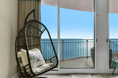 a chair on a balcony with a view of the ocean at Aqua 0904 in Panama City Beach