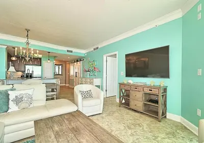 a living room with a couch and a tv on a wall at Aqua 1409 in Panama City Beach