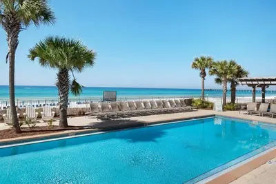 a swimming pool with chairs and the beach at Aqua 1409 in Panama City Beach