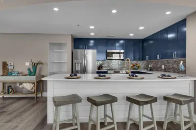 a kitchen with blue cabinets and a large counter with stools at Aqua 1801 in Panama City Beach