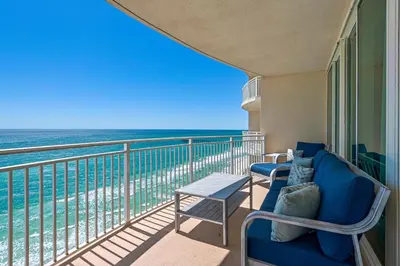 a balcony with chairs and a table and the ocean at Aqua 1801 in Panama City Beach