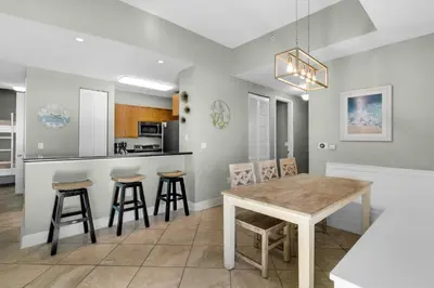 a dining room and kitchen with a table and stools at Aqua 0111 in Panama City Beach